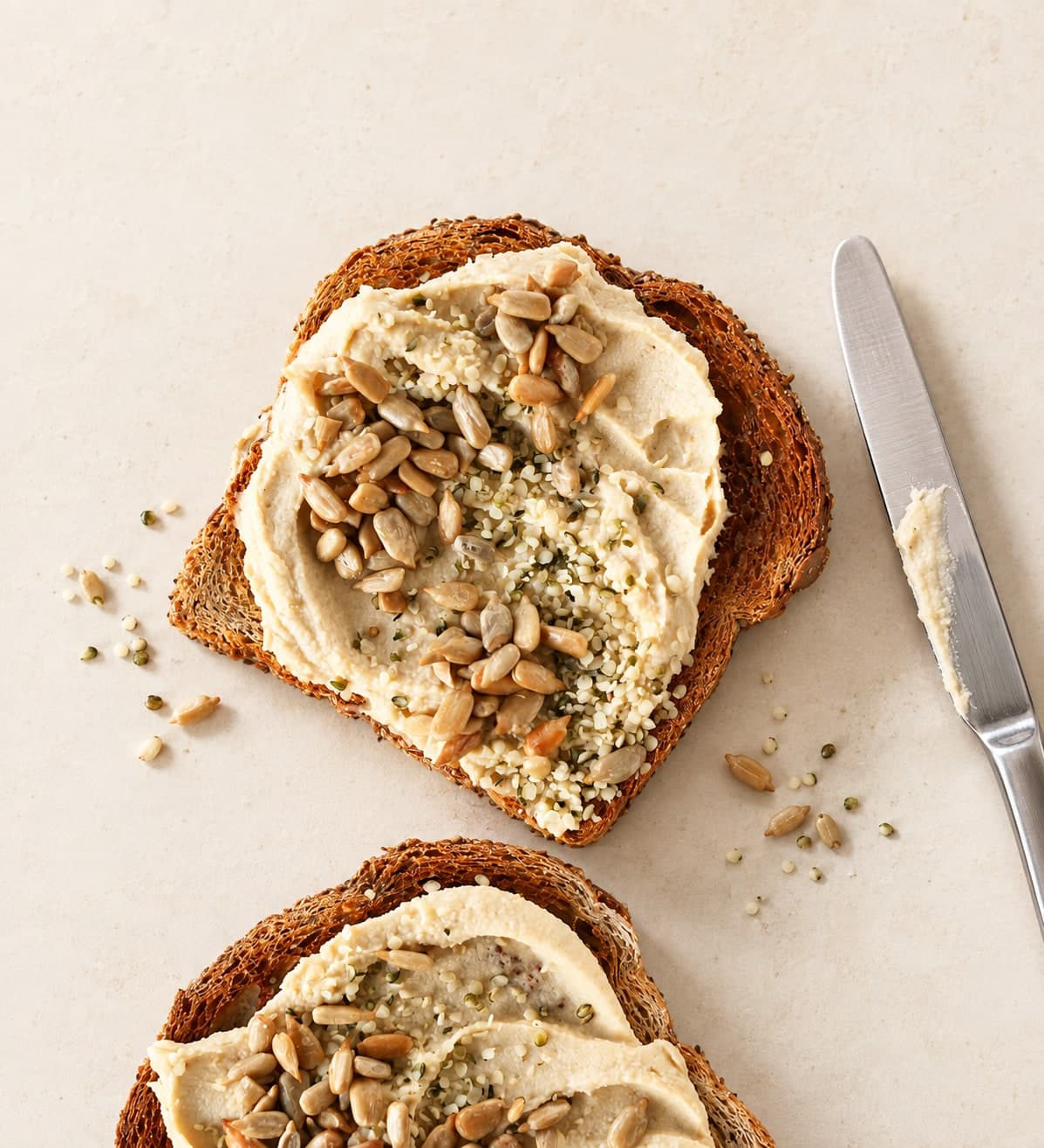 Deux tartines de houmous parsemées de graines de chanvre et de tournesol