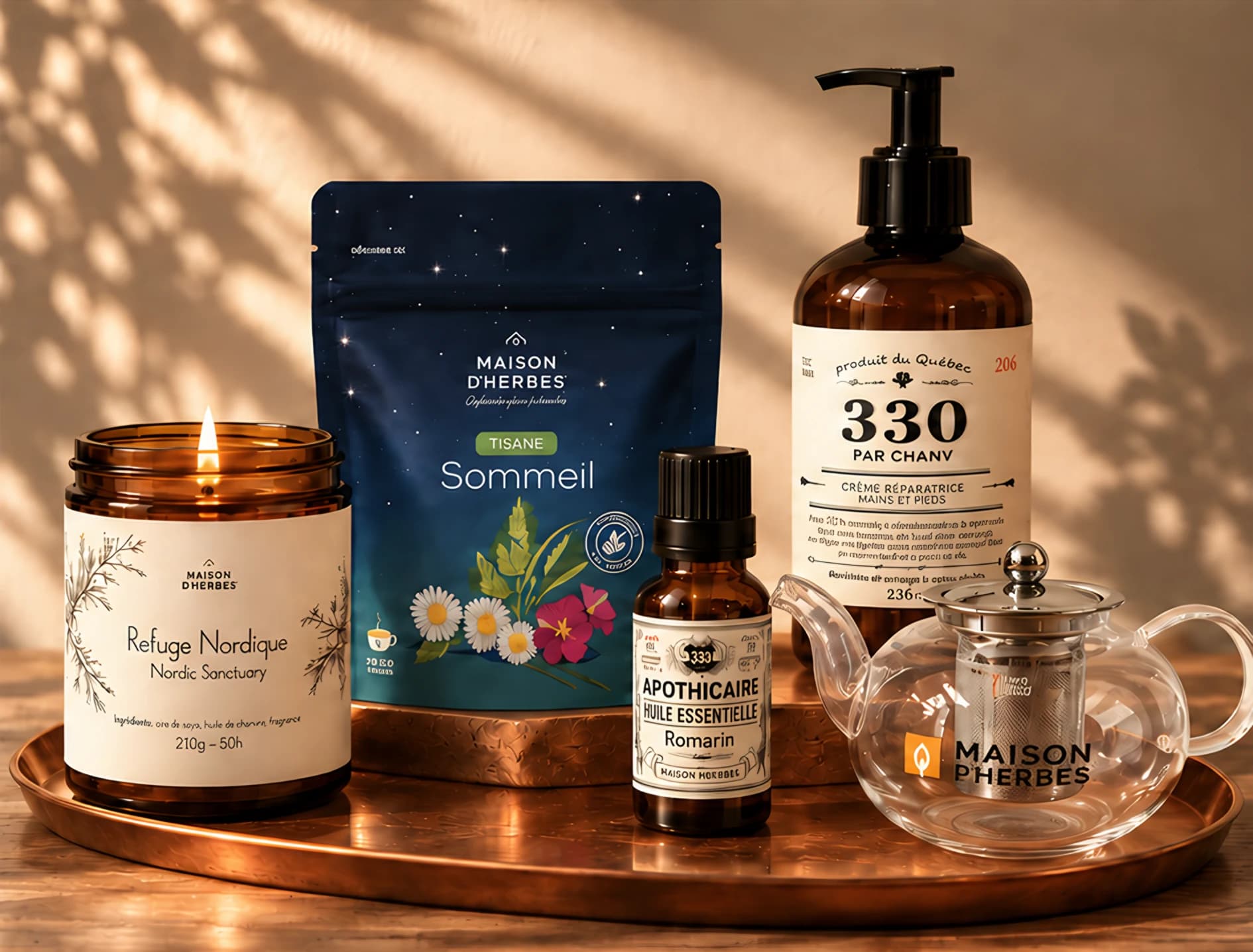 Produits en ancien emballage sur un plateau de cuivre : bougie allumée, sachet de tisane Sommeil, crème mains et pieds, huile essentielle de romarin et théière de verre