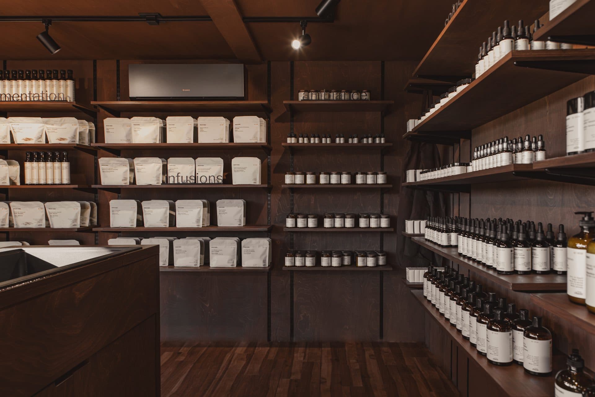 Intérieur de la boutique, ses rayonnages de bois garnis de sachets d’infusion, de pots et de flacons ambrés