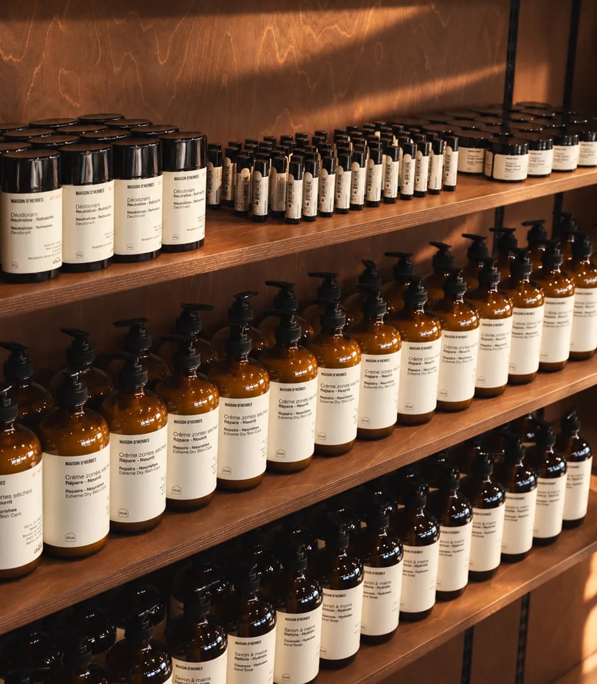 Tablettes de bois de la boutique garnies de déodorants, de crèmes zones sèches et de savons à mains en flacons ambrés