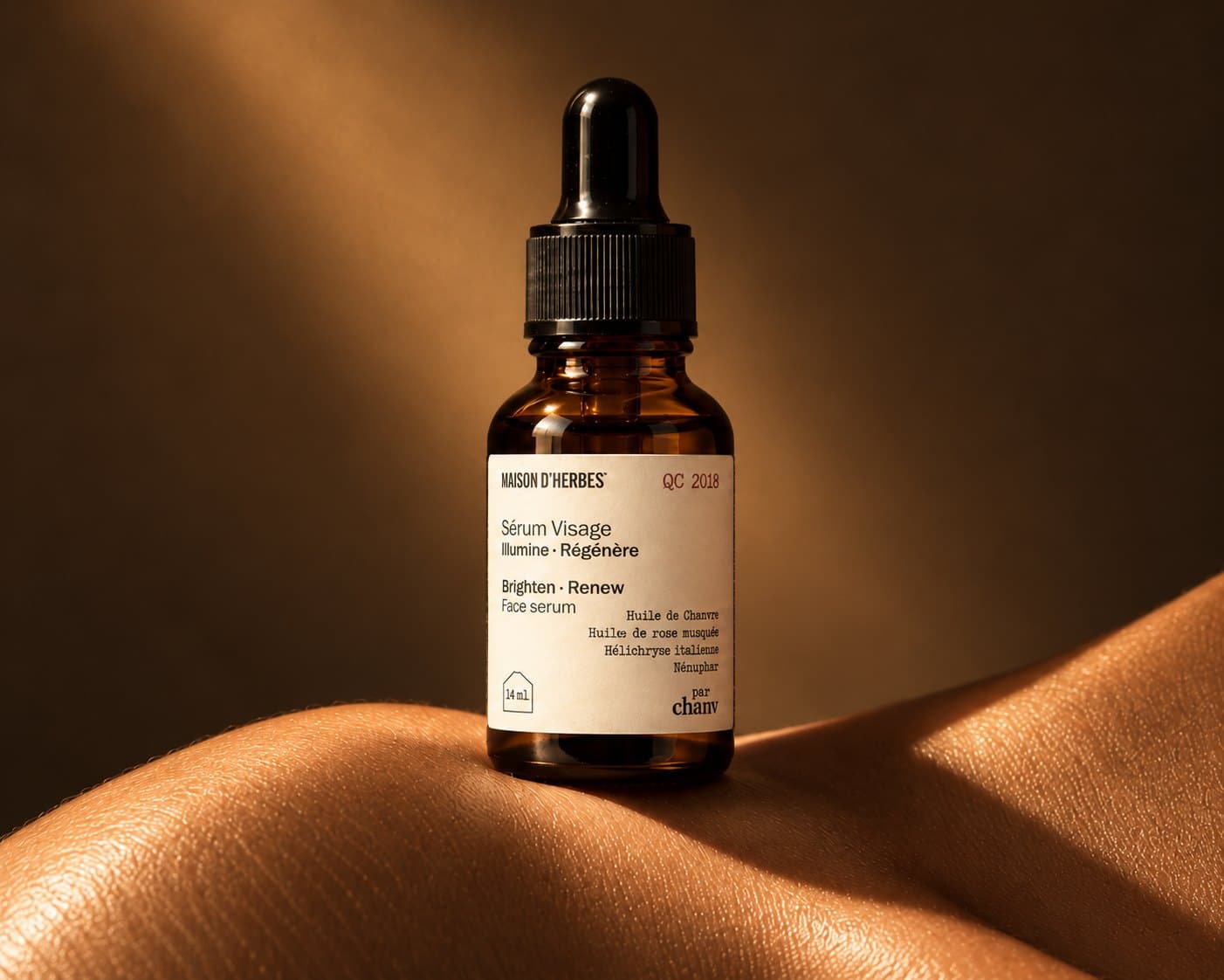 Flacon compte-gouttes de Sérum Visage Maison d’Herbes posé sur une peau, dans une lumière chaude