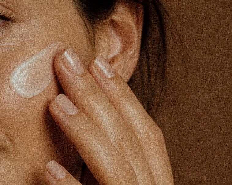Gros plan d’une joue où une noisette de crème est étalée du bout des doigts