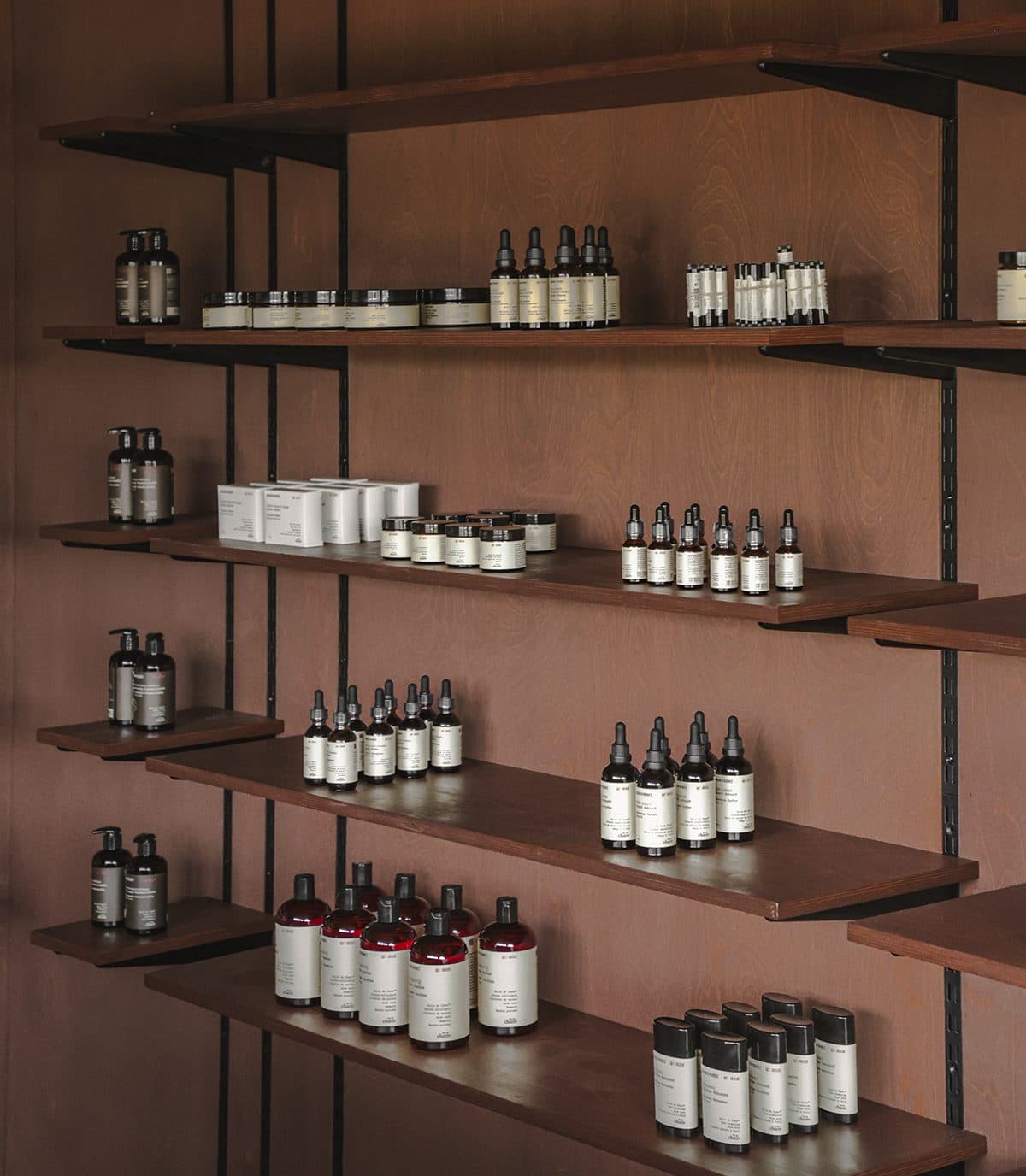 Rayonnages de bois éclairés, garnis de flacons ambrés Maison d’Herbes alignés
